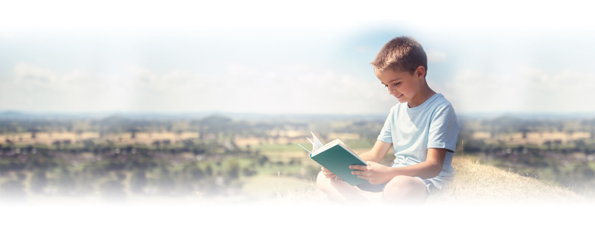 student boy sitting on ground reading book