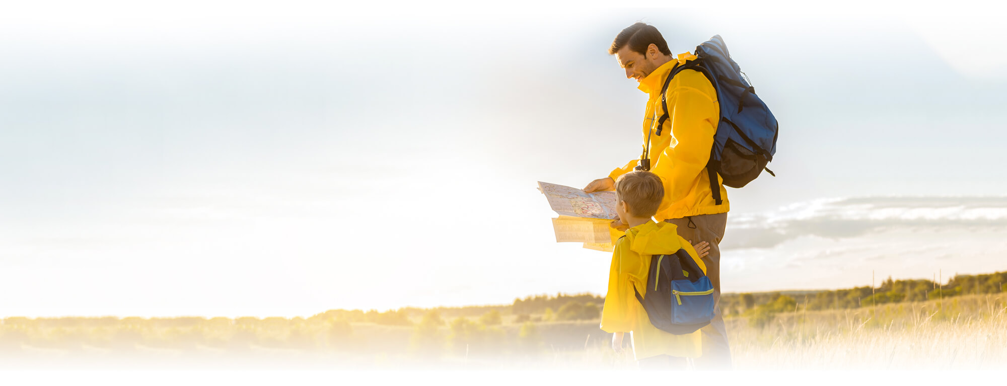 man and young boy with backpacks reading map