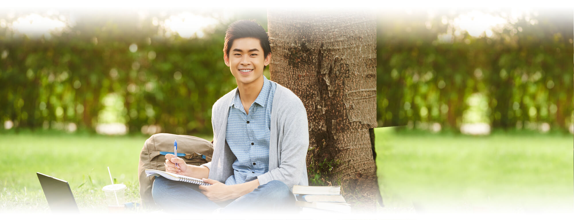 high school boy studying under a tree