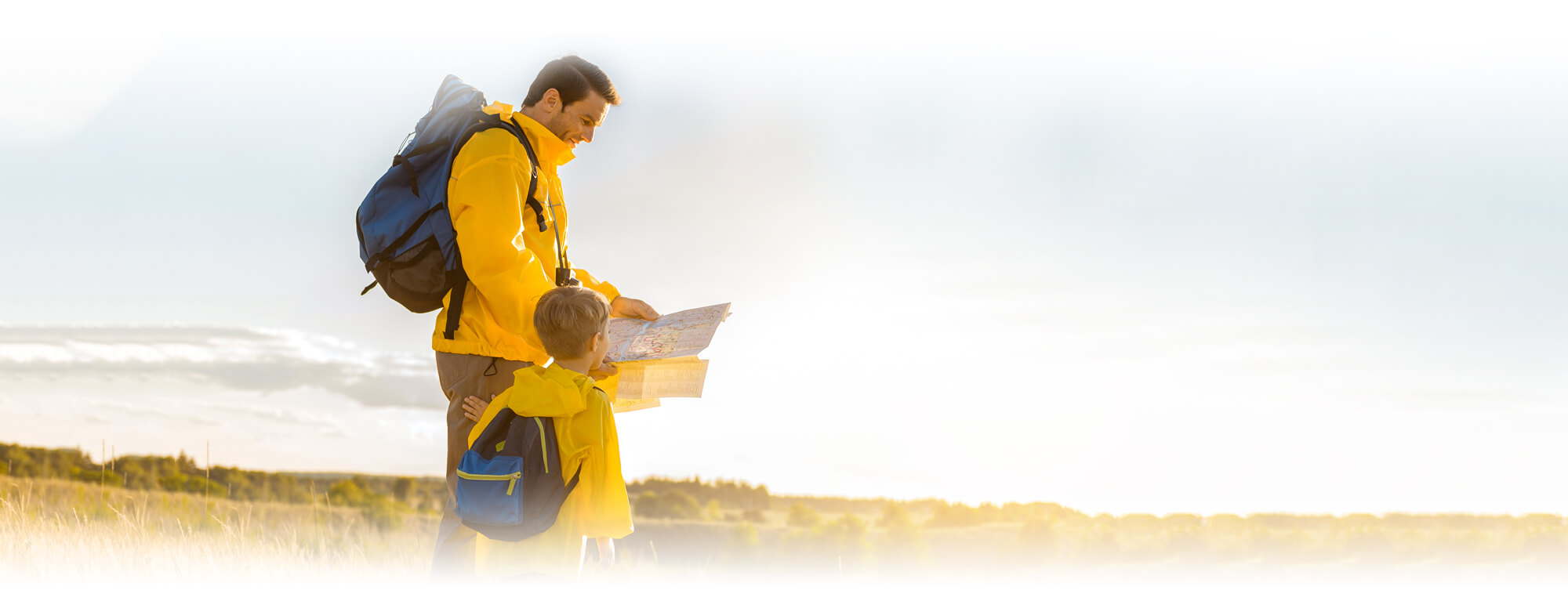 Dad and second grade or third grade boy with backpacks reading map